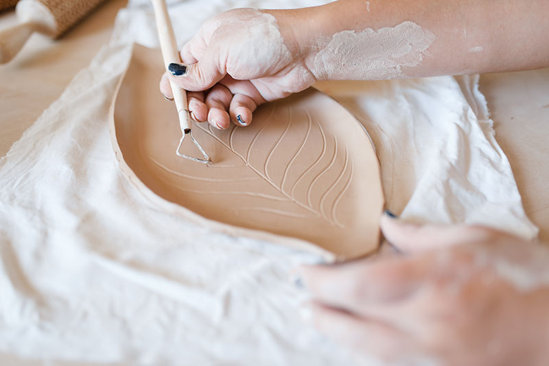 female-potter-draws-a-pattern-pottery-workshop-XWPCZ9D.jpg